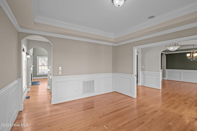 empty room featuring an inviting chandelier, crown molding, and a tray ceiling