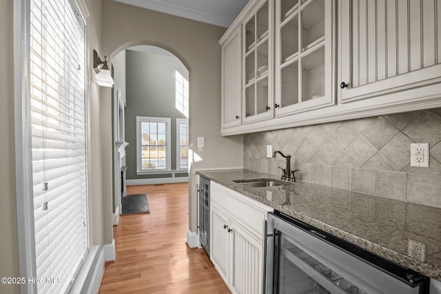 kitchen with wine cooler, sink, dark stone countertops, and white cabinetry