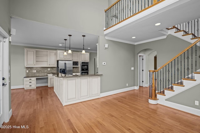 kitchen with decorative light fixtures, backsplash, stainless steel appliances, and ornamental molding