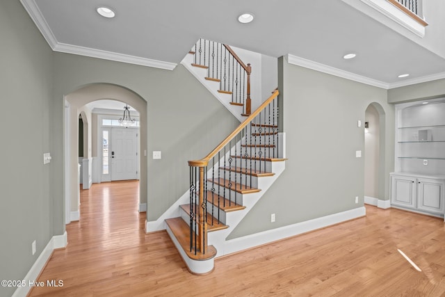 stairs featuring hardwood / wood-style flooring, built in features, and crown molding