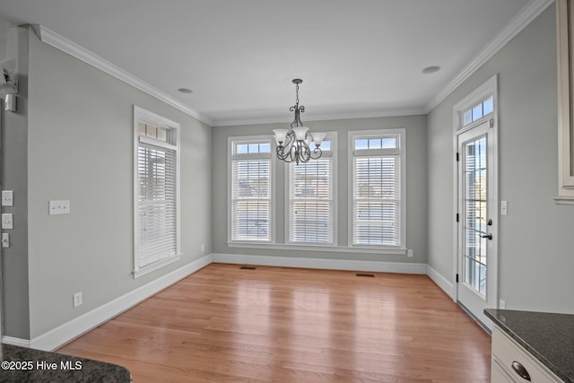 unfurnished dining area with light wood-type flooring, a chandelier, and crown molding