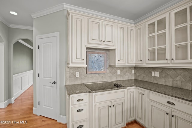 kitchen with white cabinets, dark stone countertops, light hardwood / wood-style floors, ornamental molding, and black electric cooktop