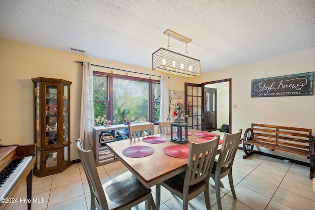 dining room with light tile patterned floors, a notable chandelier, and a textured ceiling