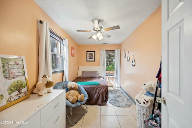 tiled bedroom featuring multiple windows, a textured ceiling, and ceiling fan