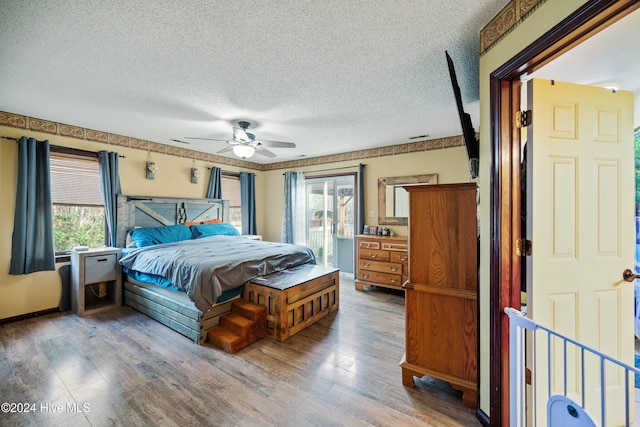 bedroom featuring multiple windows, a textured ceiling, wood-type flooring, and ceiling fan