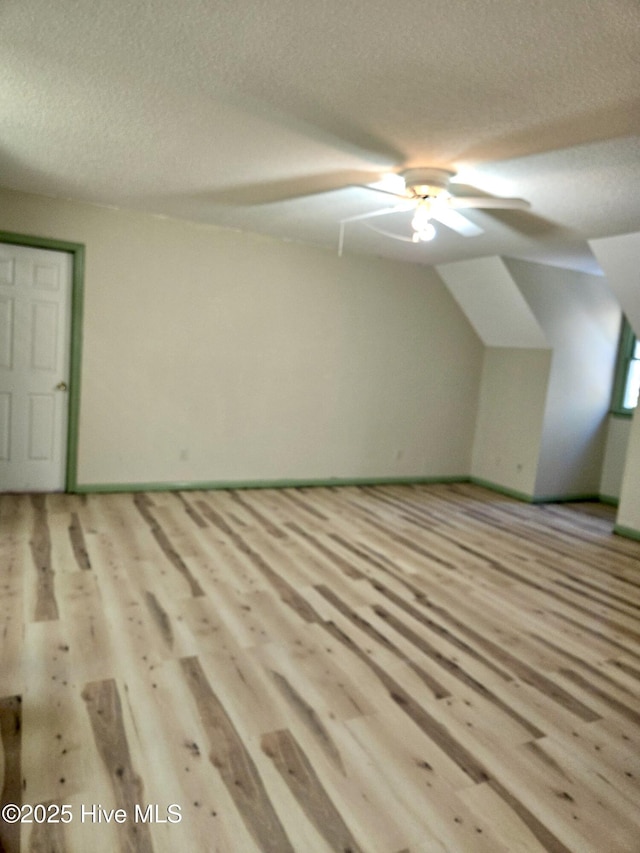 bonus room featuring ceiling fan, lofted ceiling, light hardwood / wood-style floors, and a textured ceiling