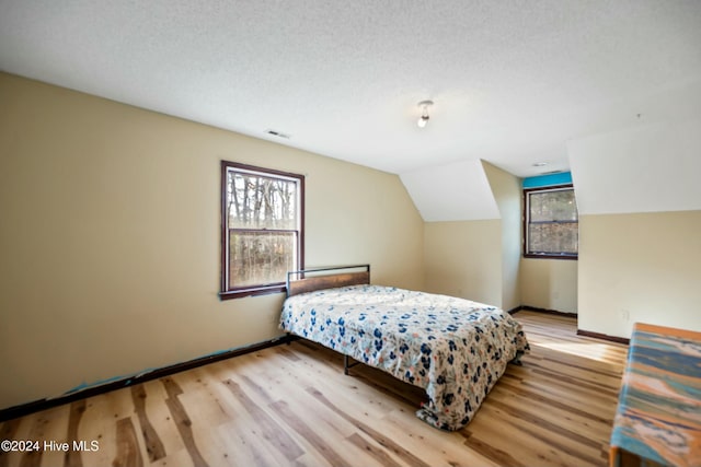 bedroom with vaulted ceiling and light wood-type flooring