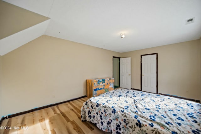 bedroom with hardwood / wood-style flooring and lofted ceiling