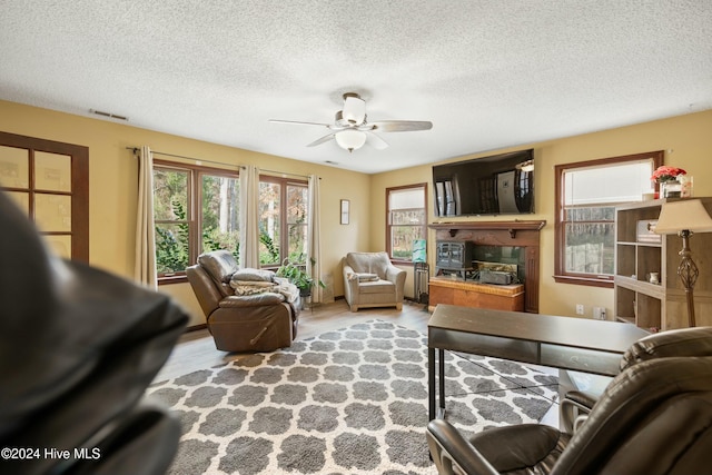 living room featuring ceiling fan, a textured ceiling, and light wood-type flooring