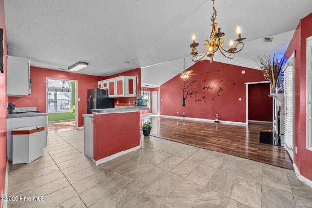 unfurnished living room with ceiling fan with notable chandelier, light wood-type flooring, a wealth of natural light, and lofted ceiling