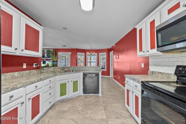 kitchen with black refrigerator, vaulted ceiling, pendant lighting, white cabinetry, and ceiling fan with notable chandelier