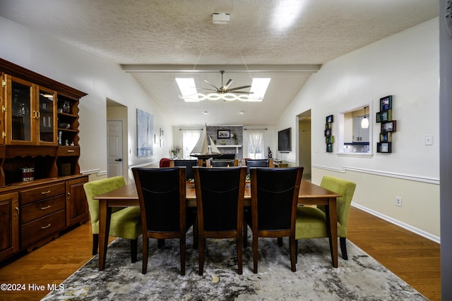 dining space featuring hardwood / wood-style floors, lofted ceiling with beams, and a textured ceiling