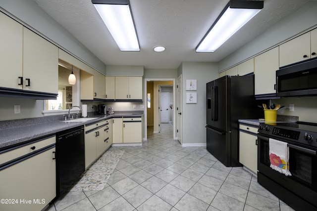 kitchen with black appliances, sink, cream cabinetry, and a textured ceiling