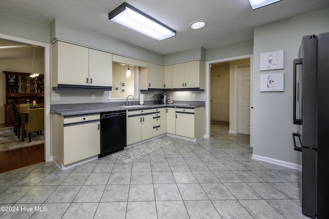 kitchen with refrigerator, sink, light tile patterned floors, a textured ceiling, and black dishwasher