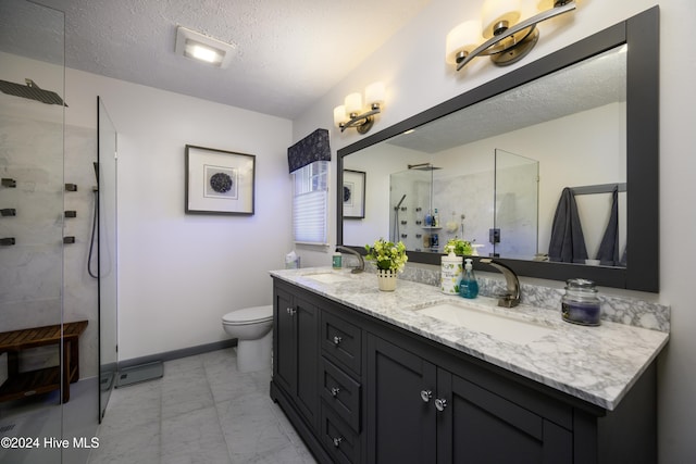 bathroom featuring vanity, toilet, tiled shower, and a textured ceiling