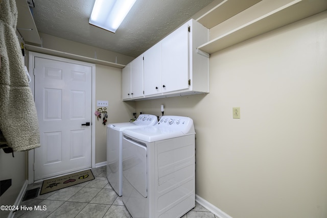 laundry room featuring separate washer and dryer, light tile patterned flooring, cabinets, and a textured ceiling