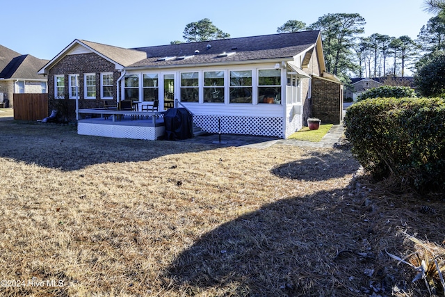 rear view of house featuring a sunroom and a deck