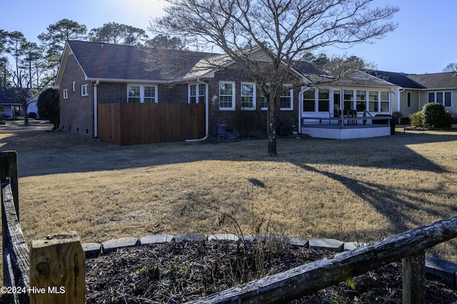 rear view of house with a lawn, a sunroom, and a deck