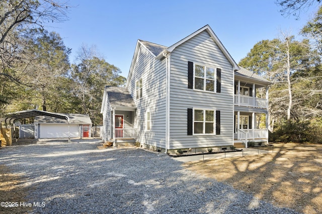 view of front of house with a balcony, an outbuilding, a carport, covered porch, and a garage