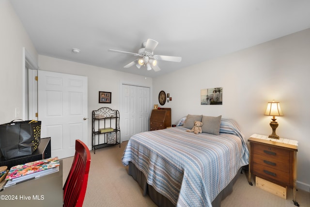 bedroom with ceiling fan, a closet, and light colored carpet