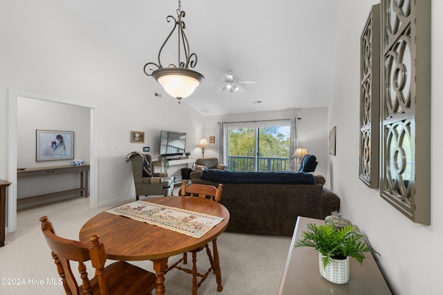 carpeted dining space with ceiling fan and vaulted ceiling