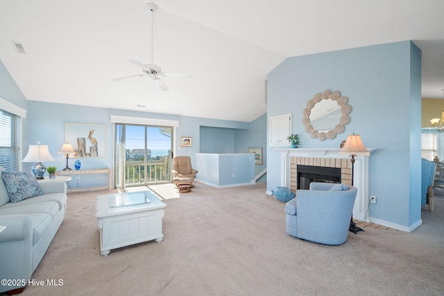 carpeted living room featuring lofted ceiling, a healthy amount of sunlight, a fireplace, and ceiling fan with notable chandelier