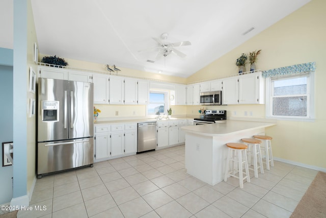 kitchen with white cabinetry, a breakfast bar area, vaulted ceiling, and appliances with stainless steel finishes