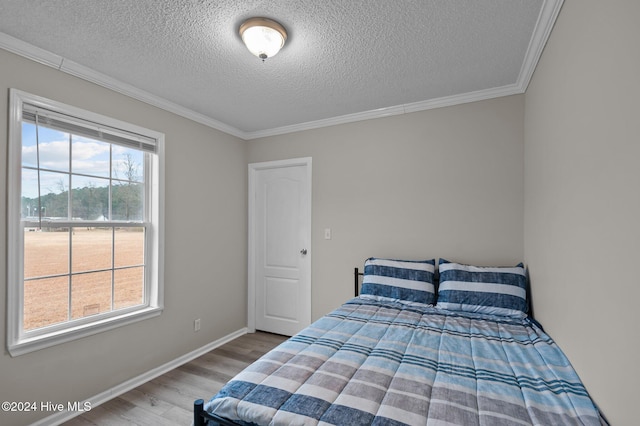 bedroom featuring crown molding, hardwood / wood-style floors, and a textured ceiling