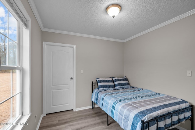 bedroom with a textured ceiling, light hardwood / wood-style flooring, and ornamental molding