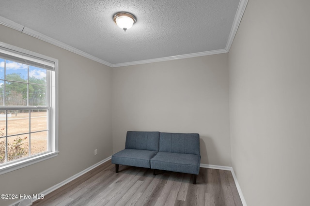 living area featuring plenty of natural light, light hardwood / wood-style floors, ornamental molding, and a textured ceiling