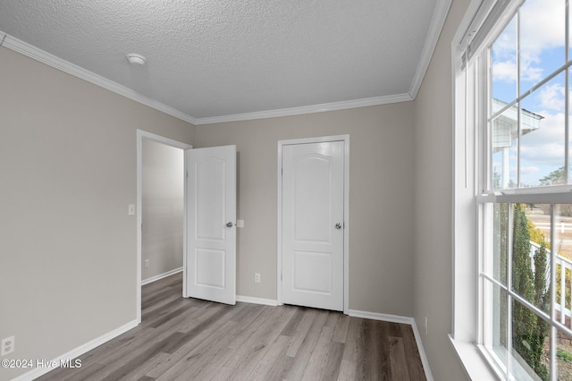 unfurnished bedroom featuring crown molding, a textured ceiling, and light wood-type flooring