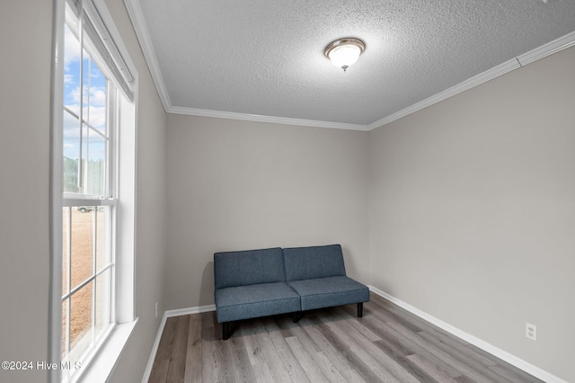 living area with ornamental molding, a textured ceiling, and light hardwood / wood-style flooring