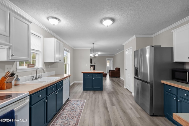 kitchen with white cabinetry, sink, blue cabinets, crown molding, and decorative light fixtures