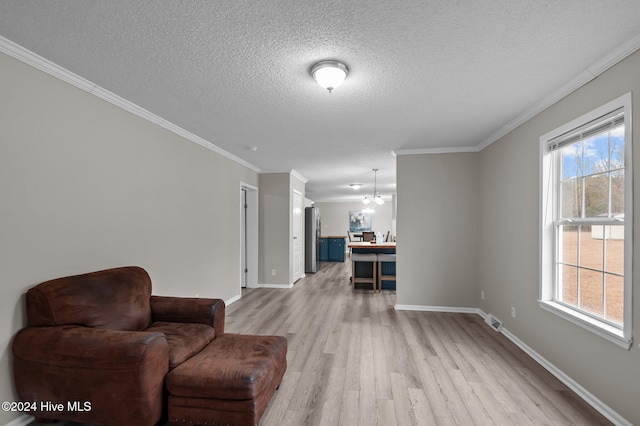 living area featuring a wealth of natural light, crown molding, light wood-type flooring, and an inviting chandelier