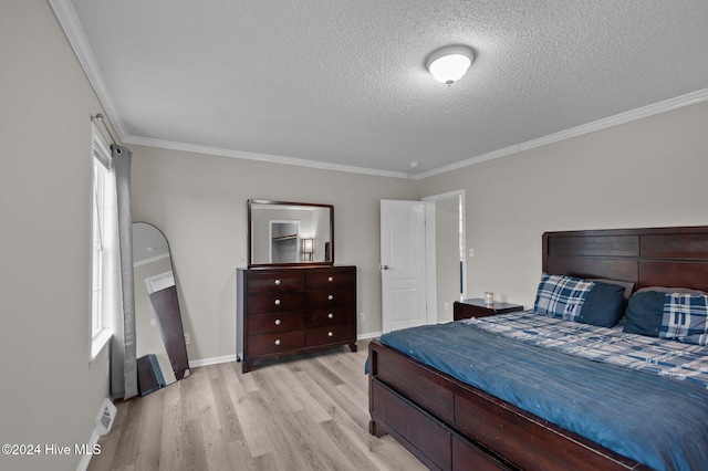 bedroom featuring ornamental molding, a textured ceiling, and light hardwood / wood-style flooring