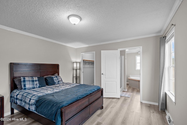 bedroom featuring connected bathroom, multiple windows, a walk in closet, a closet, and light wood-type flooring