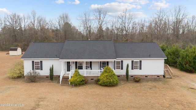 view of front of house featuring a porch and a storage shed