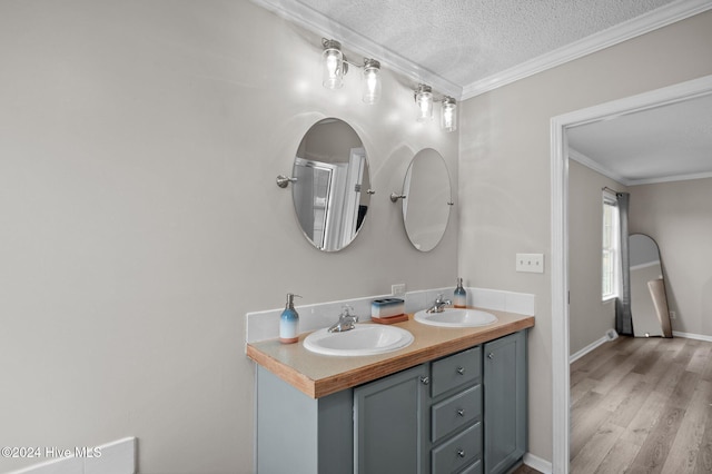 bathroom featuring crown molding, hardwood / wood-style floors, vanity, and a textured ceiling