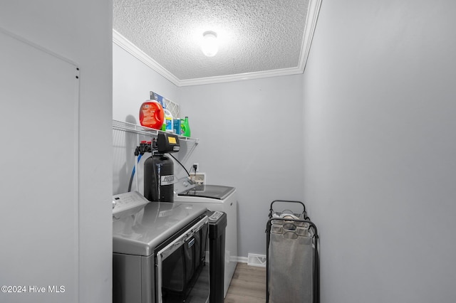 laundry area featuring ornamental molding, washer and dryer, a textured ceiling, and hardwood / wood-style flooring