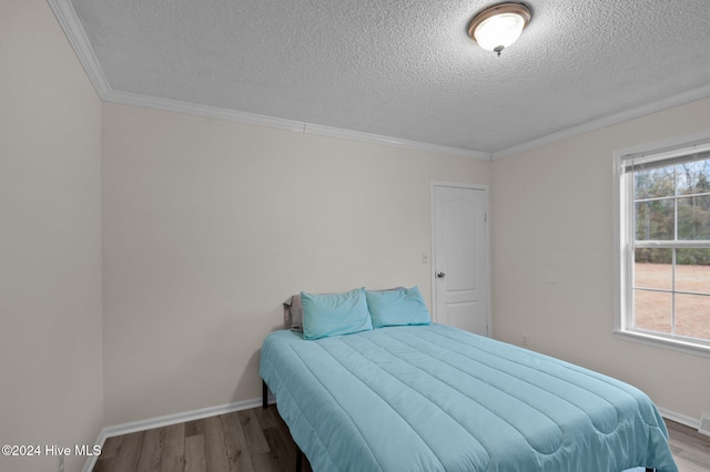 bedroom featuring crown molding, hardwood / wood-style floors, and a textured ceiling