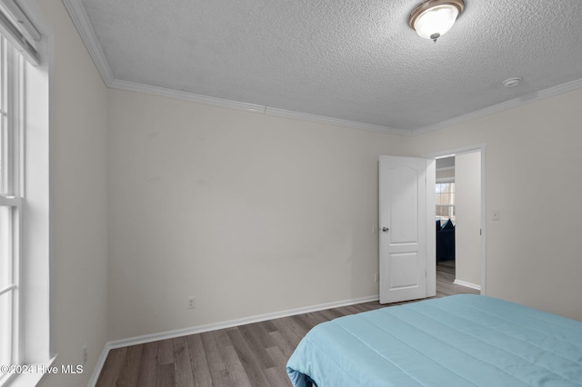 bedroom featuring wood-type flooring, a textured ceiling, multiple windows, and ornamental molding