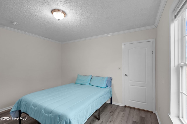 bedroom with a textured ceiling, light hardwood / wood-style flooring, and crown molding