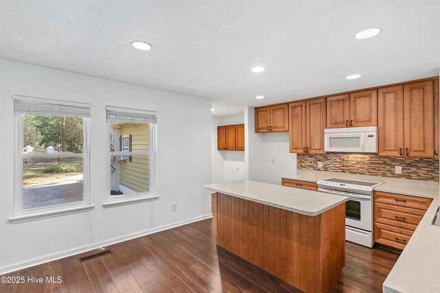 kitchen featuring white appliances, dark wood-type flooring, decorative backsplash, and a kitchen island