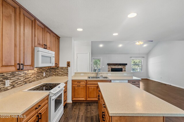 kitchen with sink, dark hardwood / wood-style floors, white appliances, a fireplace, and decorative backsplash