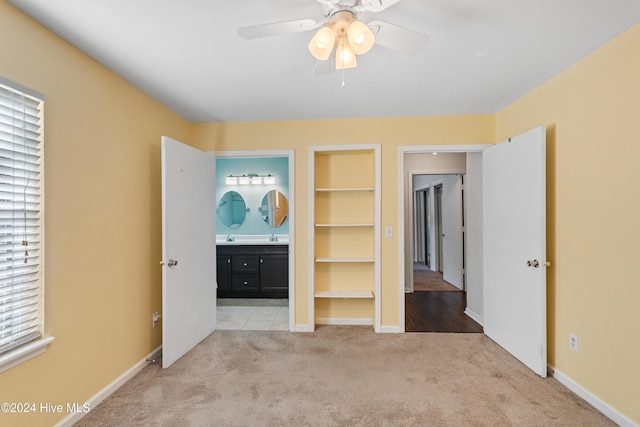 unfurnished bedroom featuring light carpet, multiple windows, baseboards, and ensuite bathroom