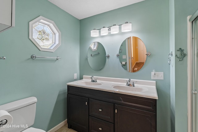 full bathroom featuring double vanity, a sink, toilet, and baseboards