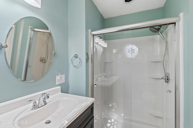 full bathroom featuring a stall shower, vanity, and a textured ceiling