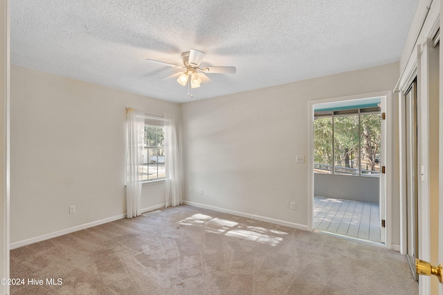 spare room with baseboards, a textured ceiling, a ceiling fan, and light colored carpet