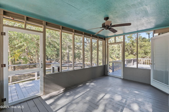 unfurnished sunroom featuring a ceiling fan and plenty of natural light