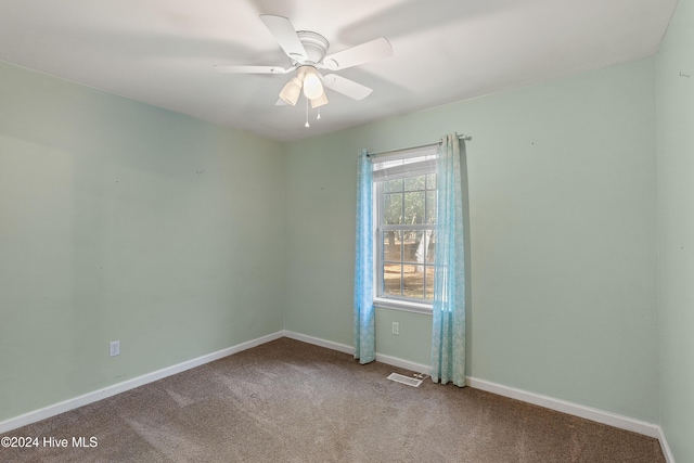 spare room with ceiling fan, carpet floors, visible vents, and baseboards